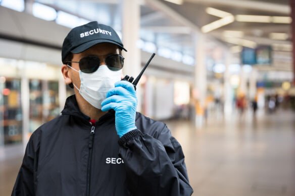 Security,Guard,Standing,In,Face,Mask,In,Airport,Terminal