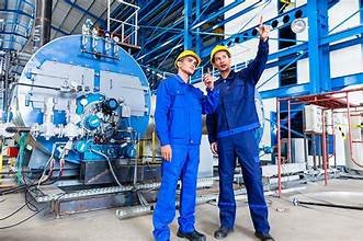 Two engineers pointing above them while standing infront of machinery.